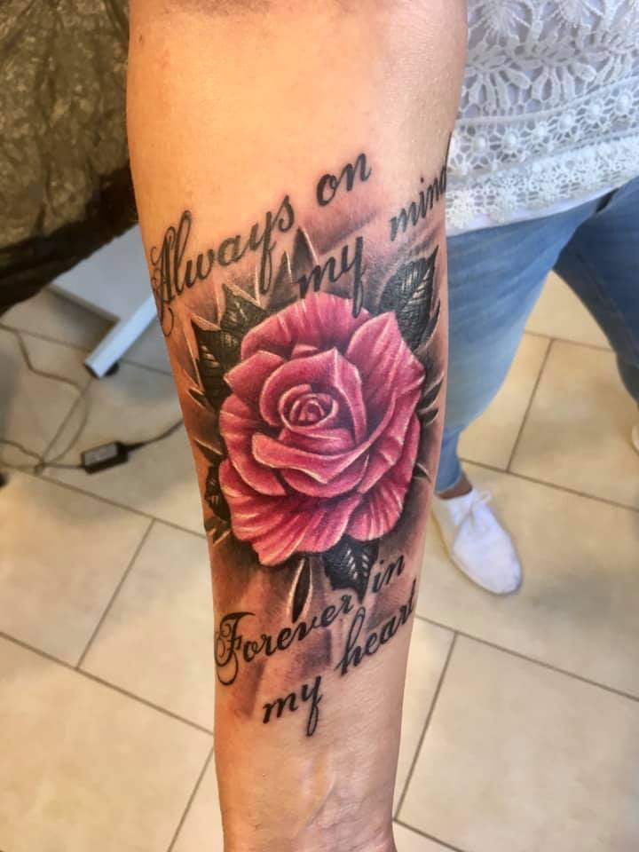 farbige Rose mit Schrift auf dem Unterarm